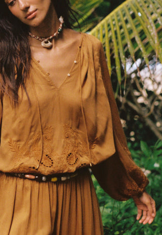  standing outdoors in front of lush green tropical foliage.
