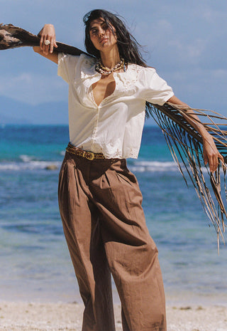 A woman stands on a beach holding a palm frond