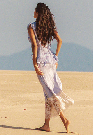 wearing a light lavender sleeveless maxi dress with ruffled shoulders and a cream lace hem.
