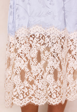 Close-up of a light blue skirt with a wide cream lace overlay hem, showing the floral lace pattern and sheer mesh underneath.
