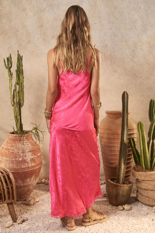 Woman in a pink dress standing among potted cacti and terracotta pots.